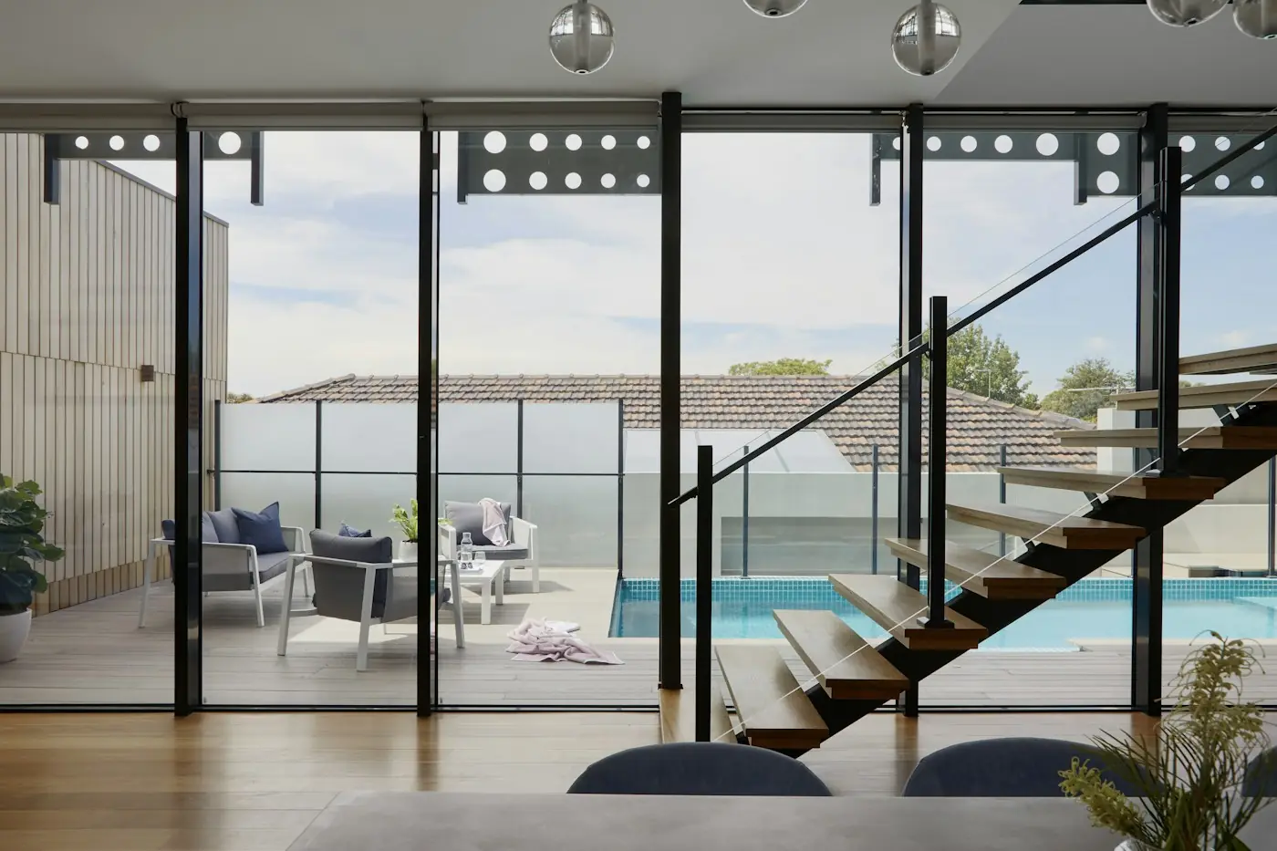 Sala con ventanales y escalera con vista a terraza